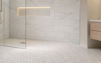 Spa-style bathroom featuring Bianco Dolomite marble shower walls, Carrara hexagon flooring and a herringbone mosaic niche.