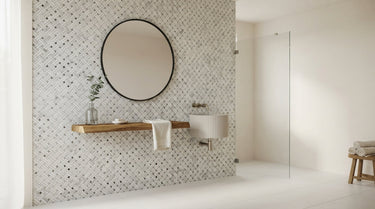 A bright bathroom featuring a sophisticated Stanza Marble mosaic tile accent wall with an intricate woven pattern in soft white and gray tones, styled with a modern round mirror in soft natural light.