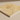 Close-up side angle showing the filled honed surface and straight edge of a 12x12 gold yellow travertine tile