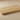 Close-up side angle showing the tumbled surface and softened edge of a horizontal 3x6 gold yellow travertine tile