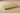 Close-up side angle showing the tumbled surface and softened edge of a horizontal 3x6 gold yellow travertine tile