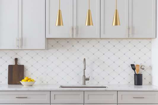 Modern kitchen with Bianco Dolomite Octave mosaic tile backsplash, light gray Shaker cabinets, brass pendant lights, and marble countertop