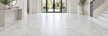 White marble floor tile with a mosaic border in a bright entryway