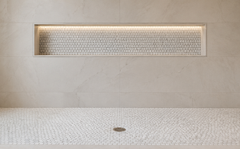 Bianco Carrara marble penny round mosaics installed on a walk-in shower floor and recessed niche wall.