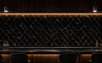 Nero Marquina marble lantern mosaic installed as an illuminated backsplash behind a spacious dark home bar.