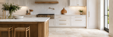 Bright kitchen featuring a Bianco Carrara marble herringbone backsplash and Ivory Travertine rectangular floor tiles.